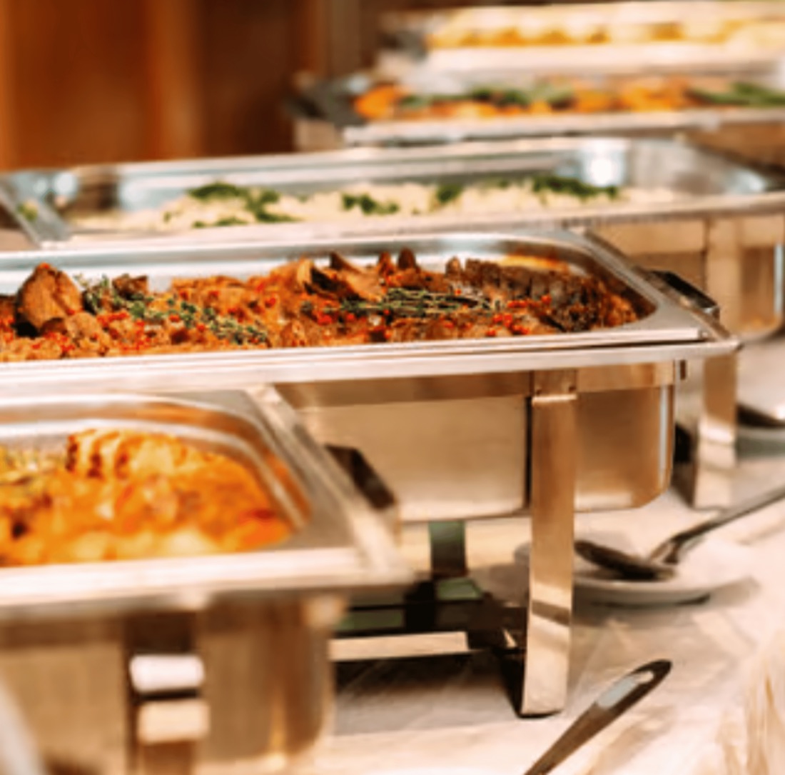 Buffet mit mehreren Chafing Dishes und warmen Speisen