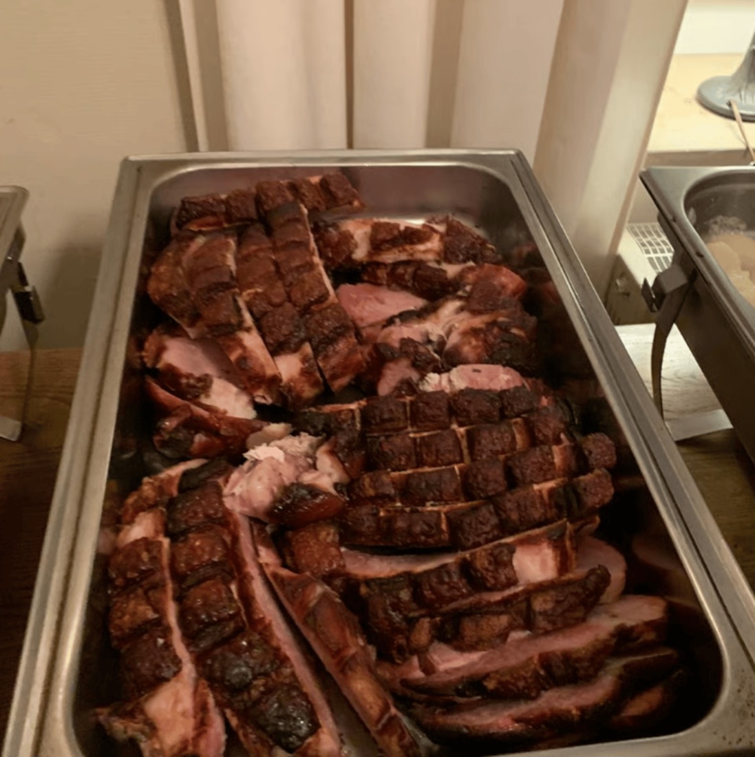 Geschnittener Schweinebraten mit knuspriger Schwarte im Buffetbehälter